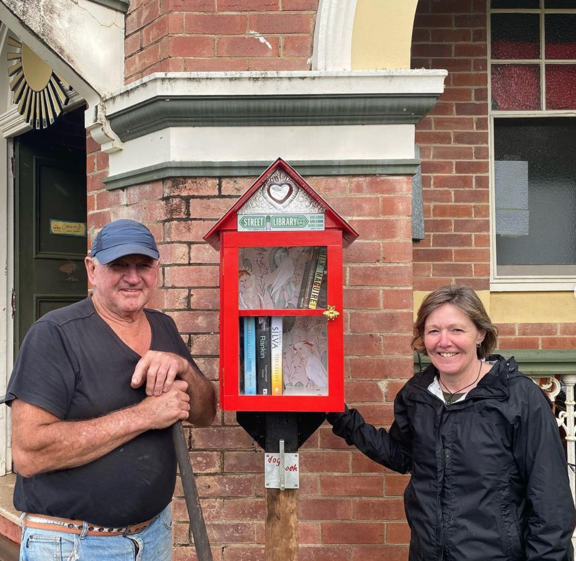 A man and woman with a handmade Street Library