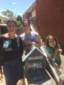 A woman and her daughters with a Street Library