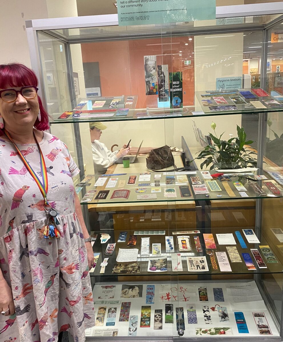 A woman standing next to a collection of items left behind in library books
