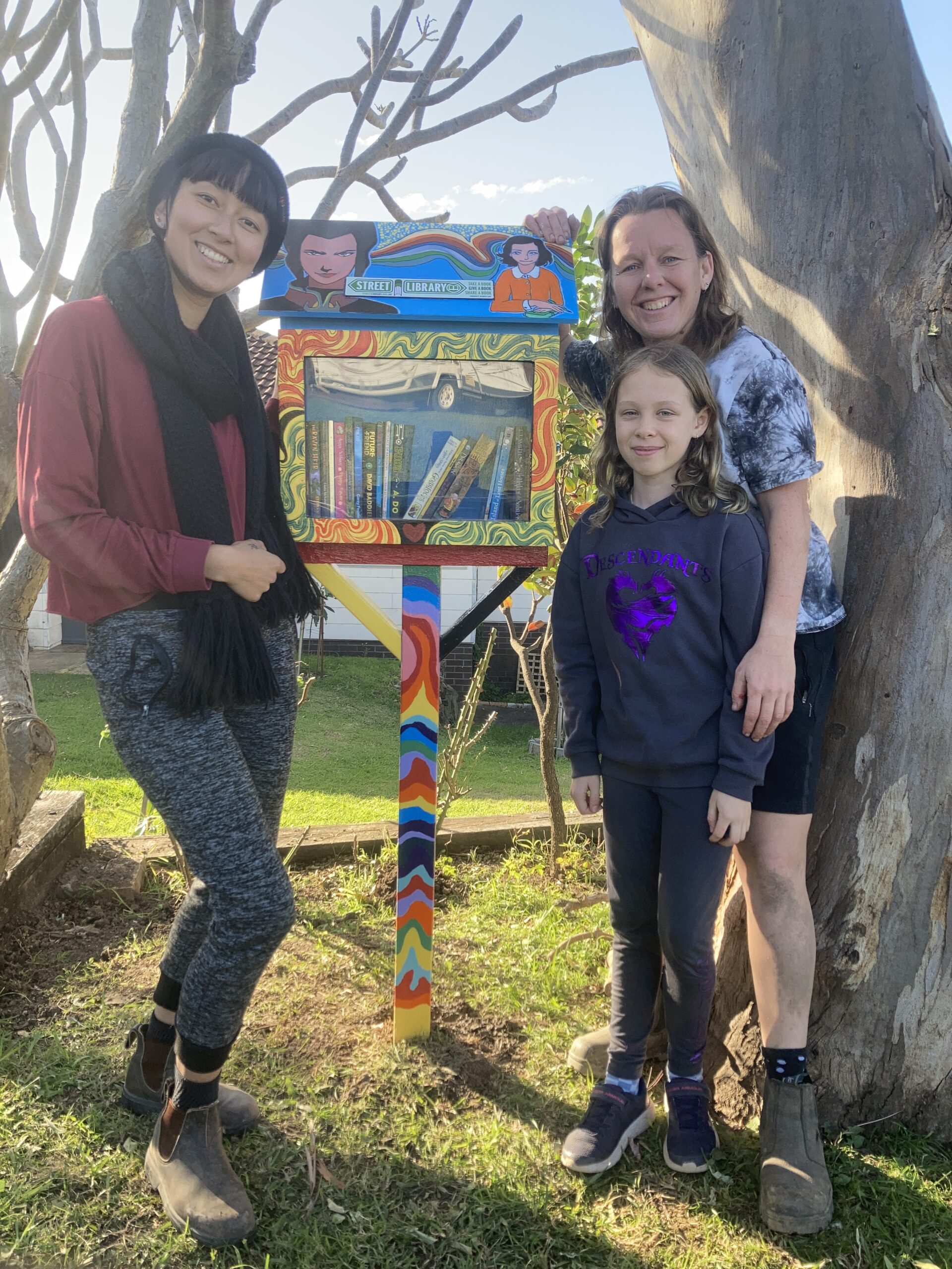 2 women and their daughter with a Street Library
